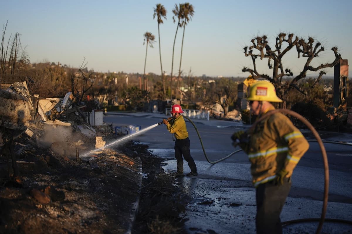 El capitán del Distrito de Bomberos de Apple Valley, Manuel Lafarga (al centro), y el bombero James Lyons apagan puntos calientes tras el incendio de Palisades en el vecindario Pacific Palisades de Los Ángeles, el lunes 13 de enero de 2025. | Crédito: AP/John Locher