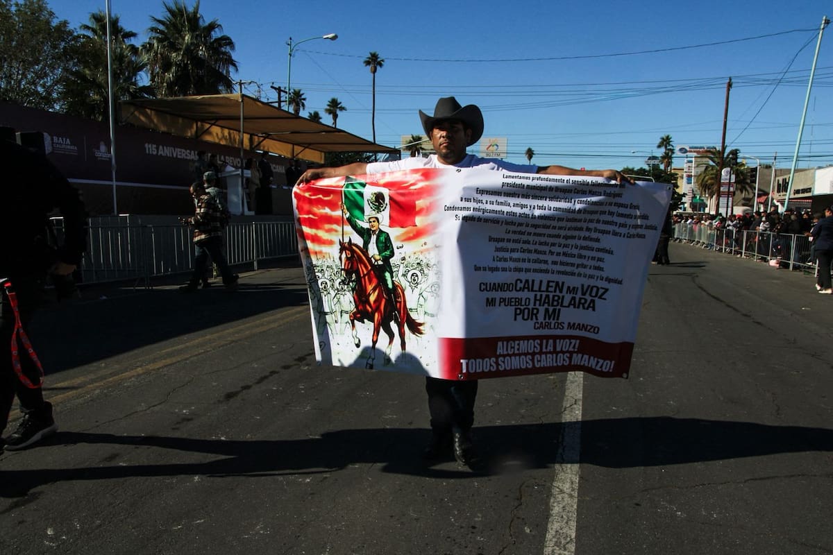 Un hombre porta una lona de protesta por el asesinato del alcalde de Uruapan, Carlos Manzo, durante el desfile del 20 de Noviembre en Mexicali. Foto: Fernando Margueri