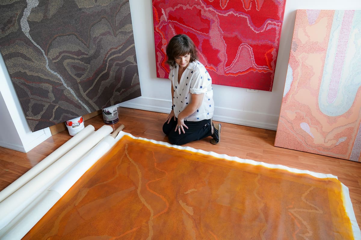 La artista brasileña Flávia Berindoague junto a sus obras en su apartamento en Brooklyn, Nueva York, el viernes 14 de agosto de 2020. Como resultado de la pandemia del coronavirus, Berindoague se vio forzada a trabajar en su casa, convirtiendo en estudio su sala. (AP Foto/John Minchillo)