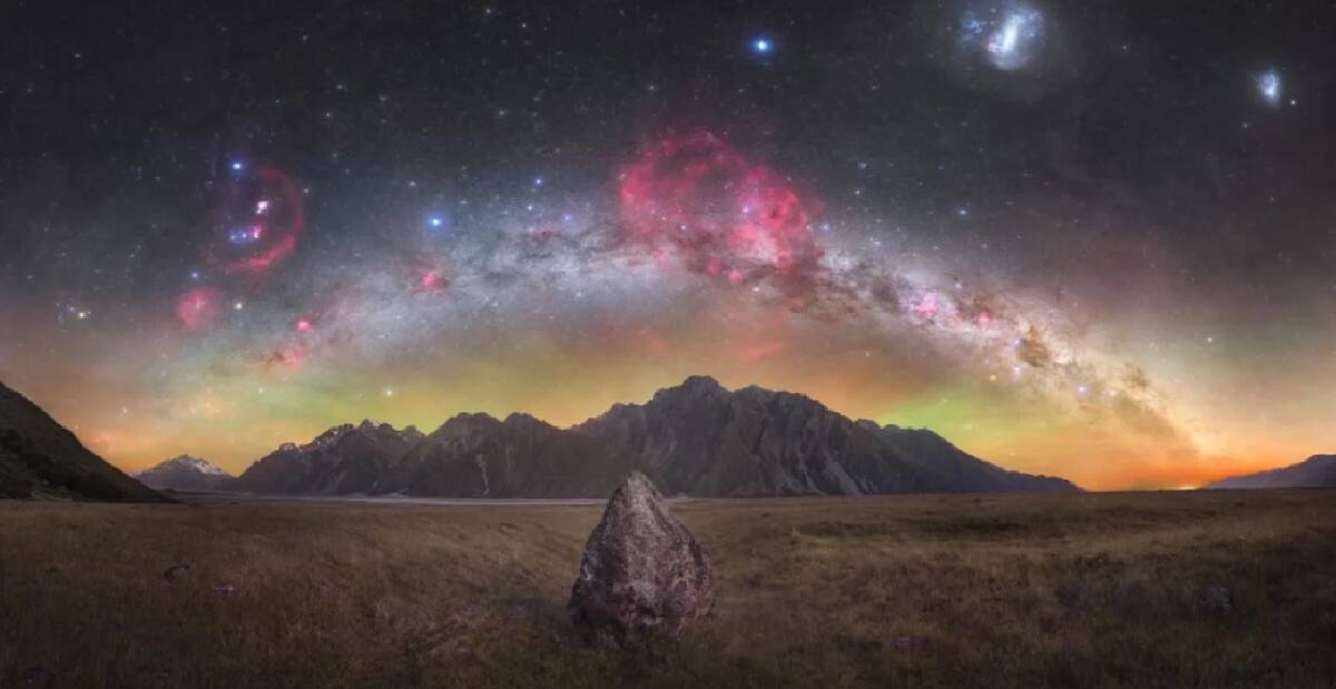 Tom Rae de Nueva Zelandia fue nombrado ganador de la categoría Skyscapes con esta imagen de los picos del Valle de Tasmania bajo un cielo nocturno, con las nubes de hidrógeno de la Nebulosa Gum, que se puede observar en rojo en el centro.