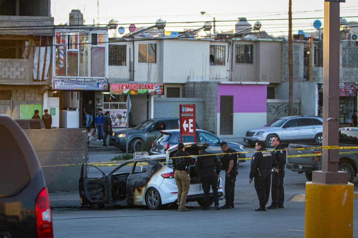 Autoridades localizaron tres cadáveres dentro de un automóvil incendiado en un centro comercial de la colonia Villa del Campo, en la Zona Este de Tijuana, y resguardaron el área para iniciar las investigaciones. Foto: Border Zoom