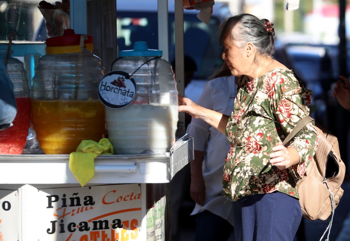 Una mujer se acerca a un puesto de aguas frescas para enfrentar el calor en Hermosillo, Sonora. | Julián Ortega