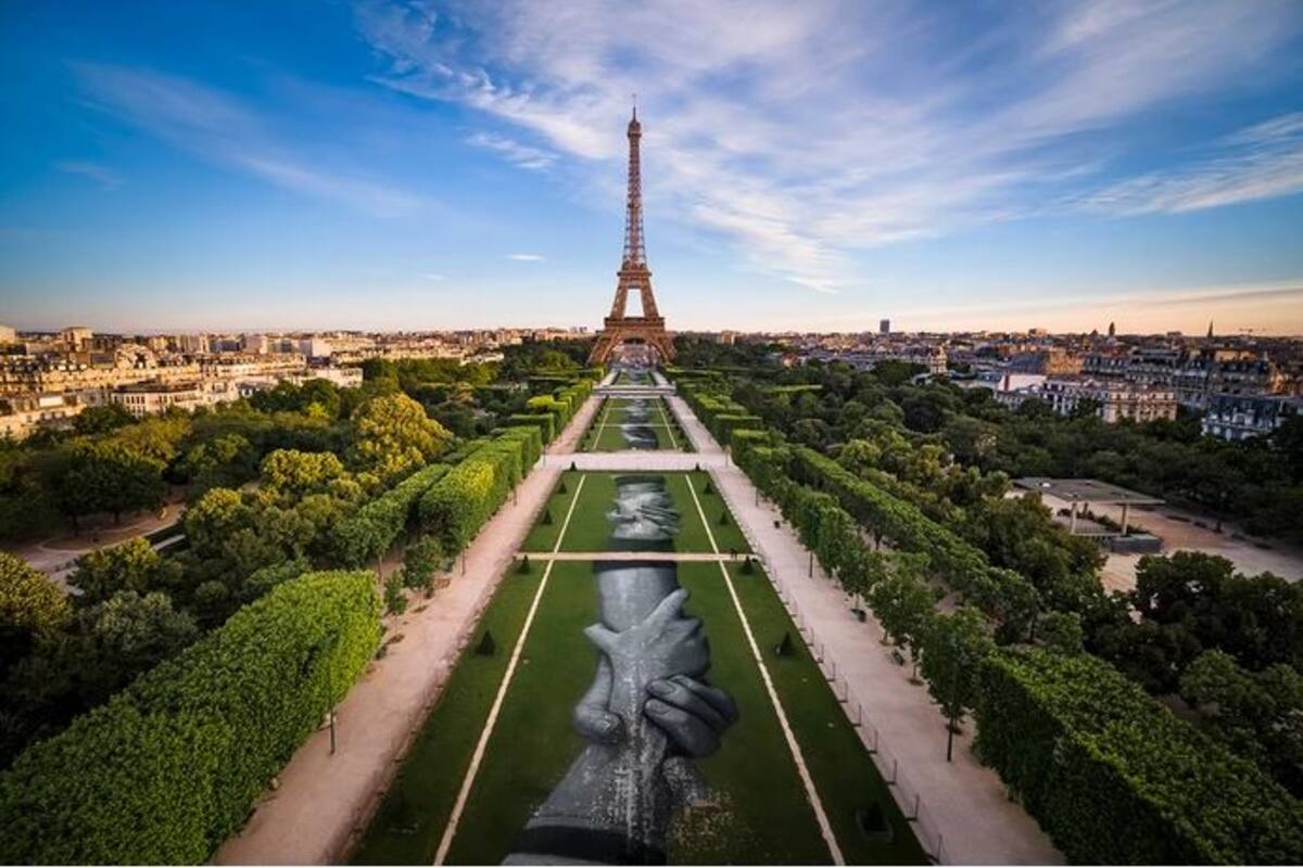 Manos de migrantes se enlazan bajo la Torre Eiffel