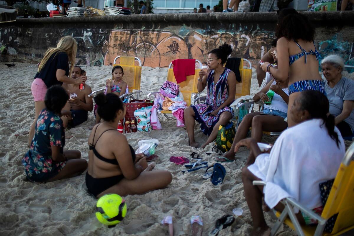 Berenice Santos, en el centro, pasa el día con su familia en la playa Arpoador en Río de Janeiro, Brasil, el 15 de mayo de 2021. La nueva versión de Anitta del clásico de la bossa nova "La chica de Ipanema" ofrece una actualización de las mujeres de Río respecto a la original de los años 60.(AP Foto/Bruna Prado)