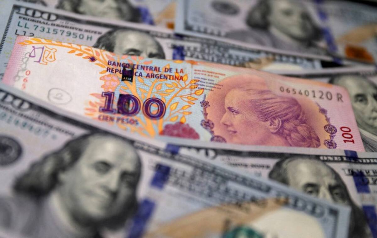 FOTO DE ARCHIVO: Un billete de cien pesos argentinos encima de varios billetes de cien dólares estadounidenses en esta foto ilustrativa tomada el 17 de octubre de 2022. REUTERS/Agustín Marcarian/