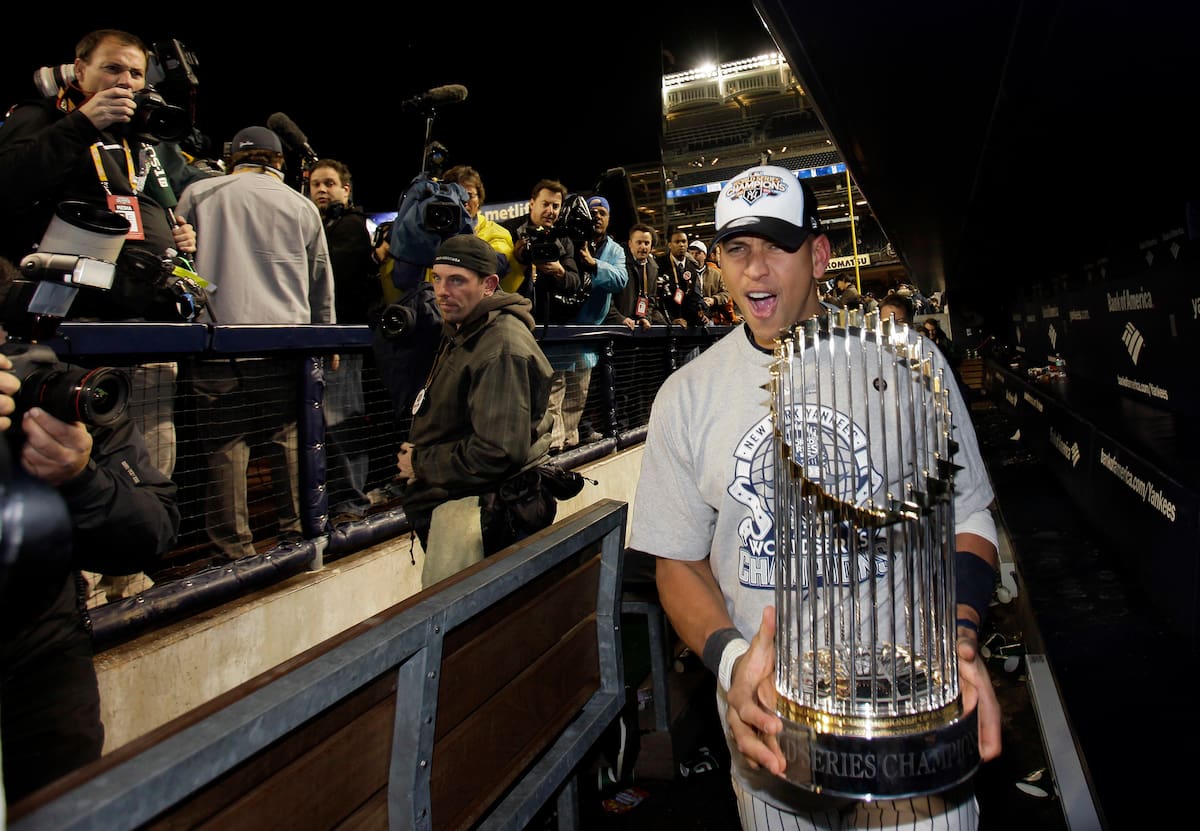 Alex Rodríguez sostiene el trofeo de campeonato de la Serie Mundial 2009 dentro del dugout del Yankee Stadium. (AP Photo/David J. Phillip, File)