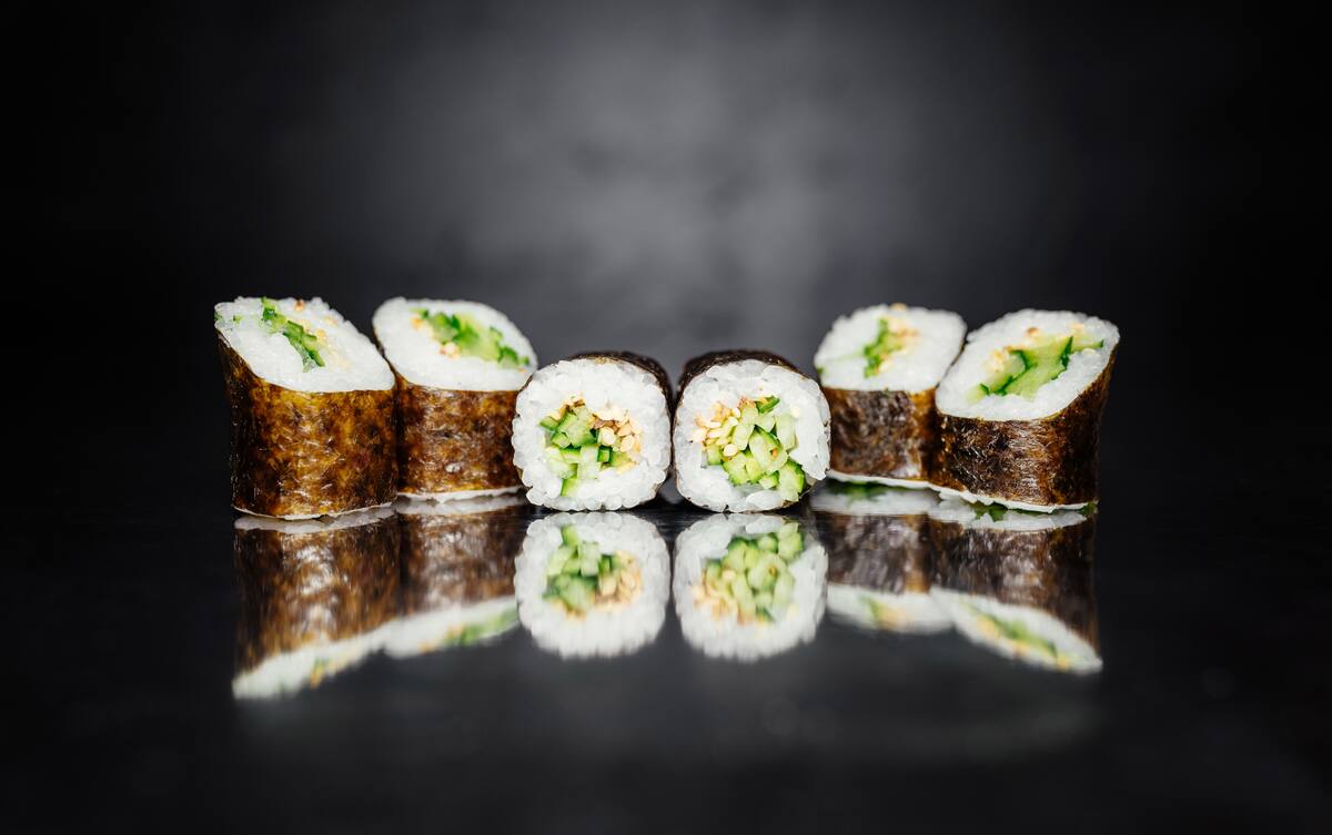 Sushi roll on dark background made of Nori, Marinated rice, Sesame white, Cucumber. Traditional Japanese cuisine. Sushi menu. Japanese food. Free-space. Close-up.