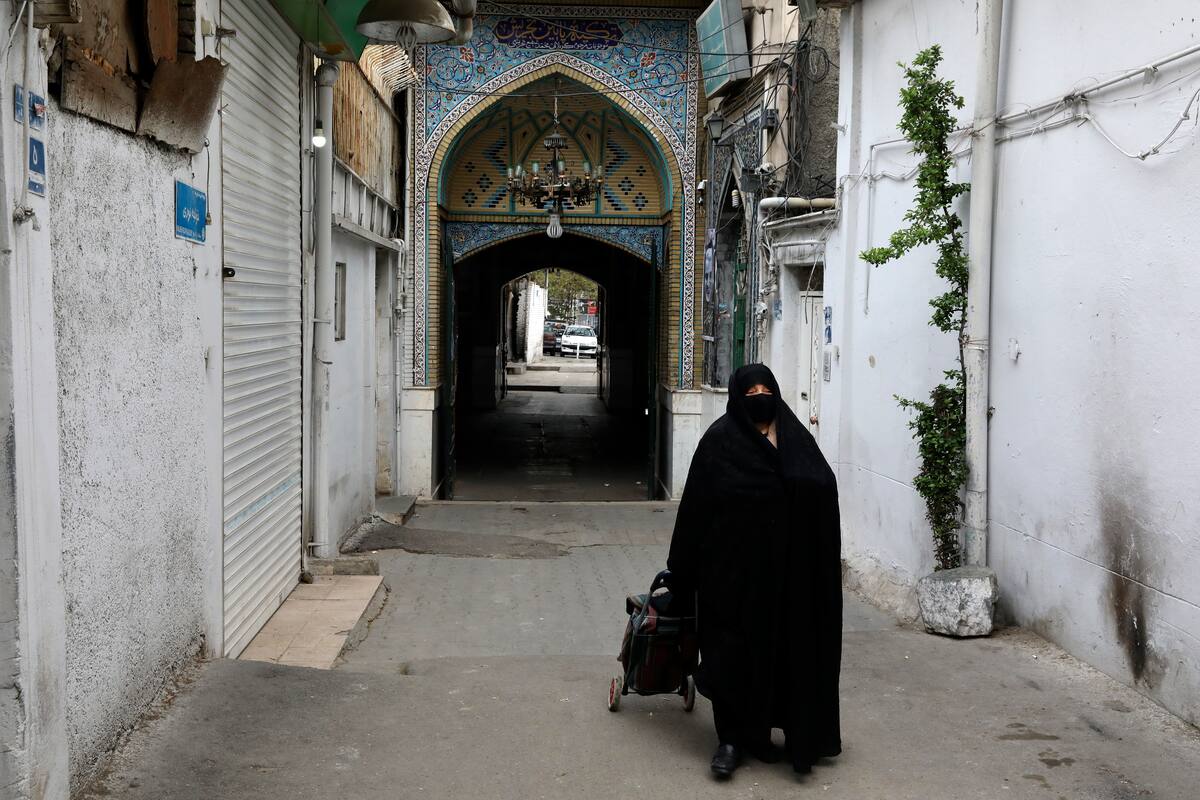 Una mujer cubierta de pies a cabeza y con una mascarilla para evitar la propagación del nuevo coronavirus, camina por el vecindario de Tajrish, en el norte de Teherán, Irán, el 16 de abril de 2020. (AP Foto/Vahid Salemi)