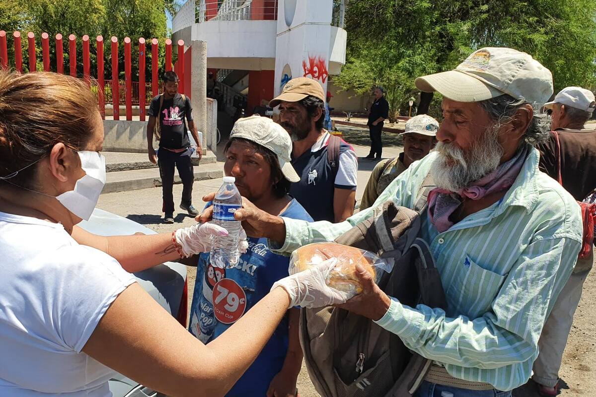 Regala mujer alimentos y agua a personas que esperan en Hospital General