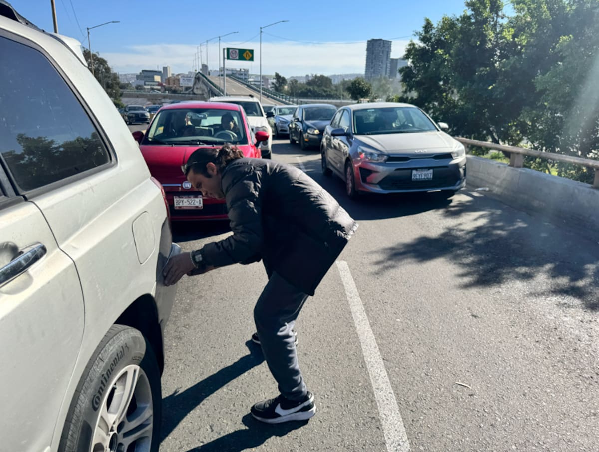 Desde la fila en la Garita de San Ysidro, Norberto Íñiguez se gana la vida reparando golpes en los autos mientras los conductores esperan cruzar la frontera. Foto: Carlos Cruz