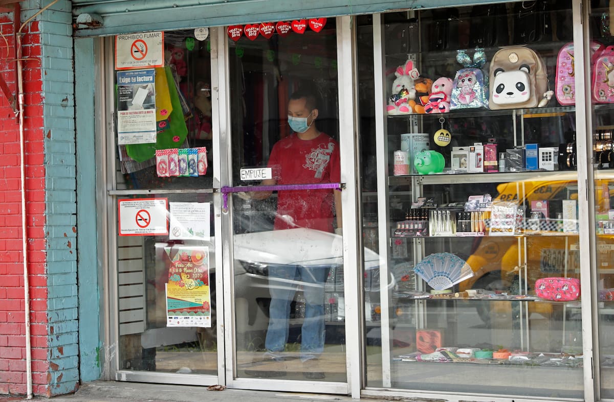 Un hombre con una máscarilla para protegerse de un posible contagio por coronavirus limpia la ventana de una tienda en el barrio "China Town" en la Ciudad de Panamá, el jueves 12 de marzo de 2020. (Foto AP/Arnulfo Franco)