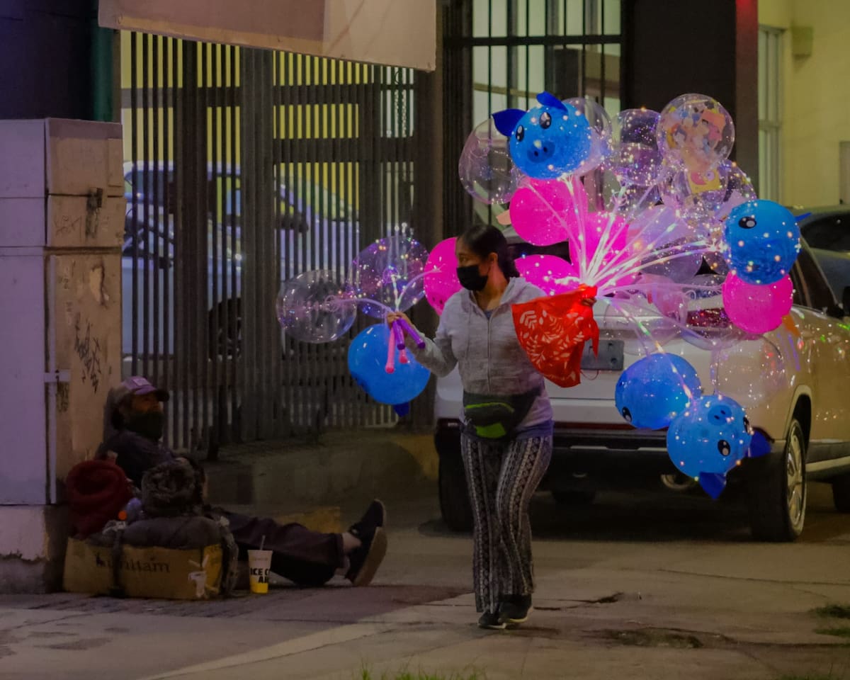 Mirada de ilusión. Durante el desfile navideño realizado el pasado jueves, un hombre en situación de calle mira con ilusión las luces de colores de los globos de una vendedora.(Foto: Javier Gallegos)