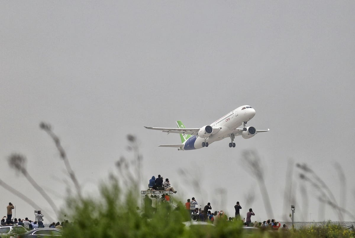 Spectators outside the airport takes photos of a C919, China's first large passenger jet, as it takes off on its maiden flight at the Pudong International Airport in Shanghai, Friday, May 5, 2017. China is touting the C919 as a rival to single-aisle jets the Airbus A320 and Boeing 737. The plane was originally due to fly in 2014 before being delivered to buyers in 2016, but has been beset by delays blamed on manufacturing problems. (Chinatopix Via AP)