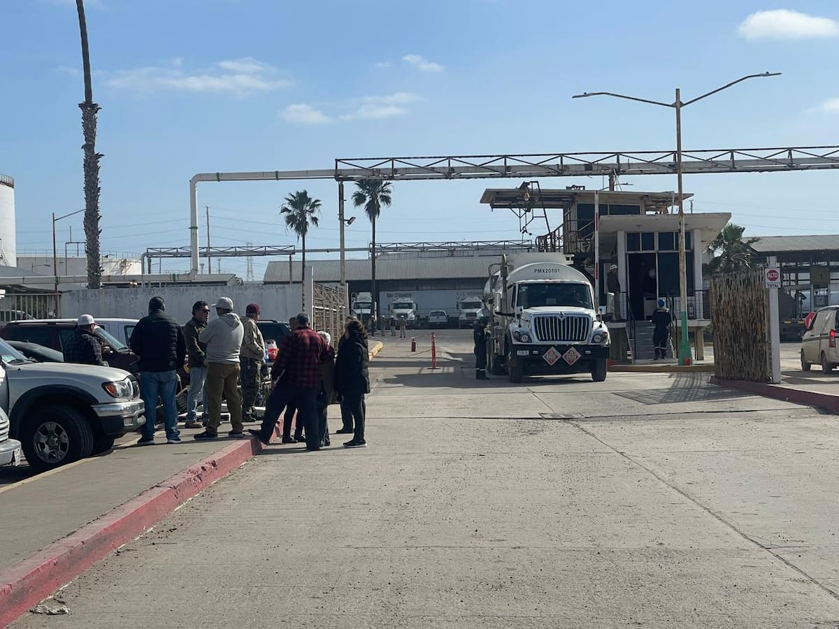 Un grupo de trabajadores jubilados permanece a las afueras de la planta.