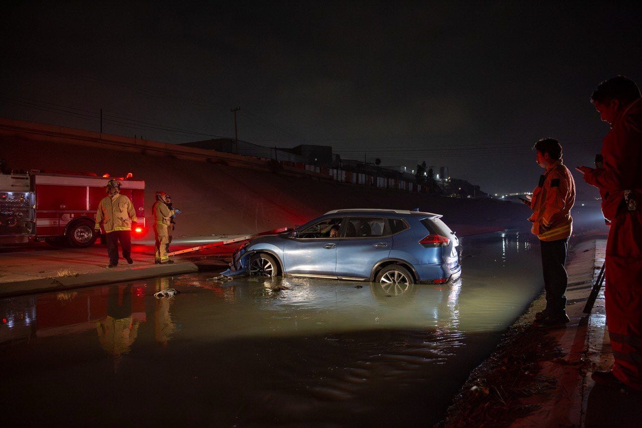 Bomberos utilizaron escaleras para rescatar a los ocupantes del automóvil que terminó dentro de las aguas negras de la canalización. Foto: Border Zoom