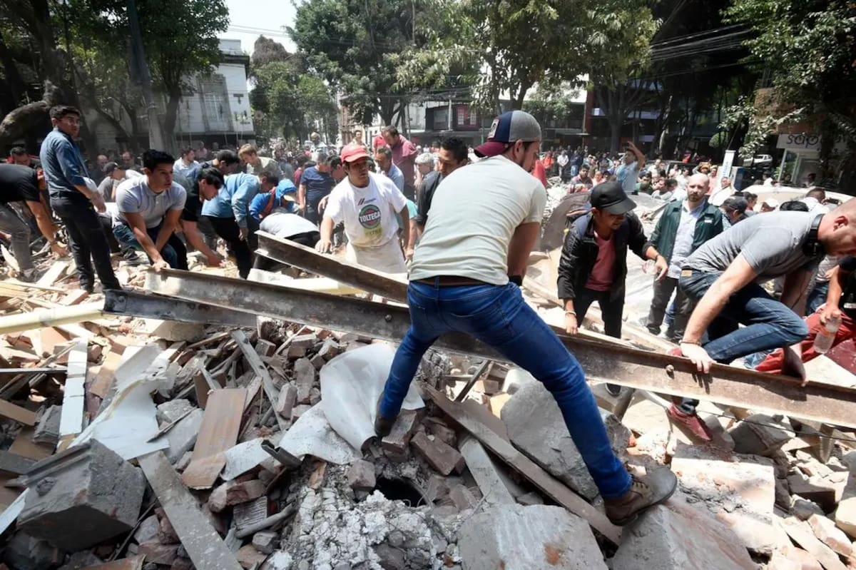 Hombres remueven los escombros de un edificio que colapsó en Ciudad de México durante el sismo.