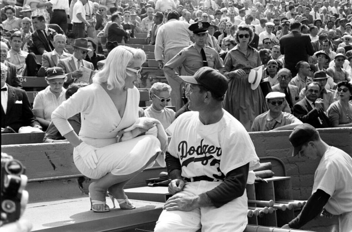 La actriz de televisión Juli Reding charla con el jardinero de los Dodgers, Elmer Valo, durante el primer juego en casa en el Coliseo de Los Ángeles, en 1958. | Foto: Shutterstock