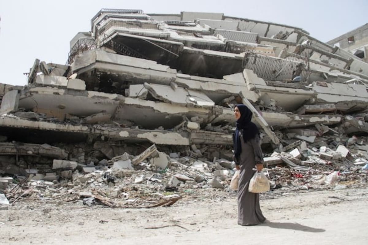 Palestinian woman Asmaa Al-Belbasi, making her way back to her shelter after buying bread from recently reopened Al-Sharq bakery, walks past the ruins of a house destroyed during Israel's military offensive, amid the ongoing conflict between Israel and Hamas, in Gaza City April 24, 2024. REUTERS/Mahmoud Issa/File Photo Purchase Licensing Rights