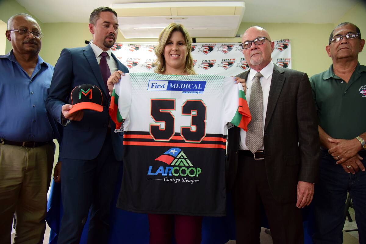 La primera base e integrante de la selección nacional de béisbol de mujeres de Puerto Rico, Diamilette Quiles Alicea, centro, posa en su presentación como la primera jugadora en firmar con los Montañeses de Utuado, uno de los equipos de la Liga Superior Doble A, en San Juan, Puerto Rico, el jueves 16 de mayo de 2019. Quiles aparece acompañada por el director ejecutivo de la Liga, Pedro Vargas, izquierda; el manager de los Montañeses, Rafael Juarbe, segundo de izquierda a derecha, el presidente de la Federación, el doctor José Quiles Rosas, segundo de derecha a izquierda, y el directior ejecutivo de la Liga de Béisbol Femenino, José Rafael Torres. (AP Foto/Carlos Giusti)