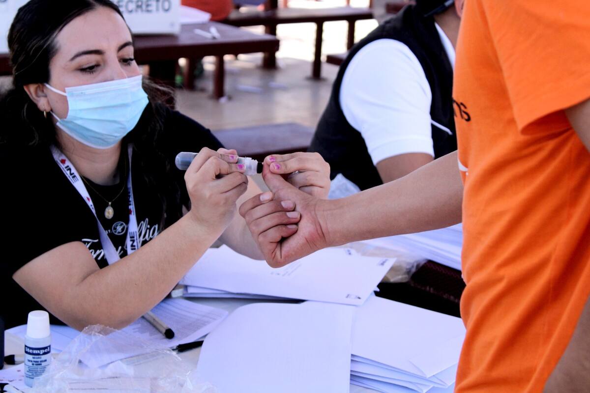Una funcionaria de casilla marca el dedo de un votante durante las elecciones en México.