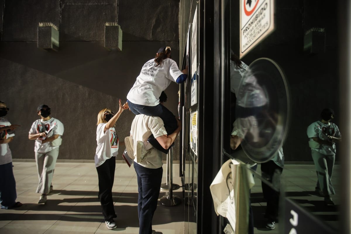 El vidrio de las puertas de cristal y ventanales estaban calientes por el sol, pero eso no fue impedimento para que las amigas de Cristina, con ayuda de otro joven, colocaran uno a uno los carteles l Foto: Juan Antonio Hernández