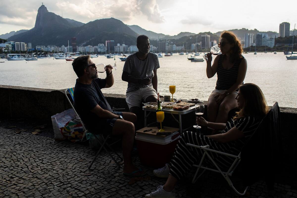Gilberto, a la izquierda, come y bebe con su esposa y amigos en el barrio de Urca en Río de Janeiro, Brasil, el domingo 16 de mayo de 2021. La nueva versión de Anitta del clásico de la bossa nova "La chica de Ipanema" ofrece una actualización de las mujeres de Río respecto a la original de los años 60. (AP Foto/Bruna Prado)