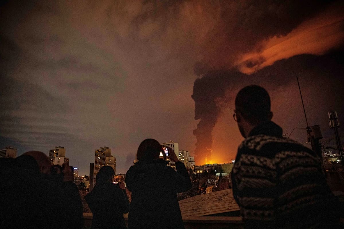 Los residentes observan y toman fotografías mientras las llamas y el humo se elevan desde una instalación de almacenamiento de petróleo atacada durante los bombardeos que sacudieron la ciudad en el marco de la campaña militar estadounidense-israelí en Teherán, Irán, el sábado 7 de marzo de 2026. (Alireza Sotakbar/ISNA vía AP)