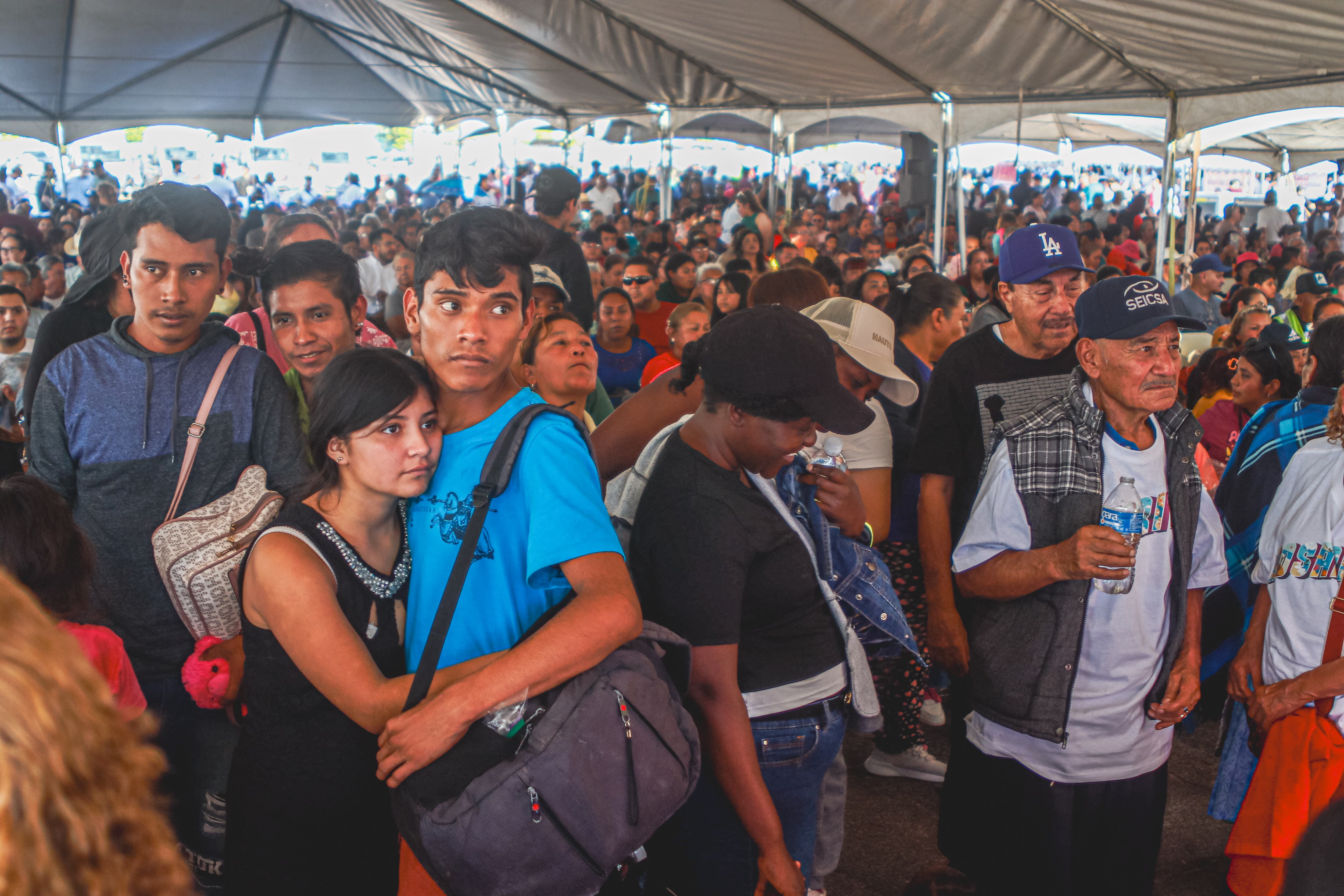 Una joven pareja, junto a varios ciudadanos, se congrega en una carpa instalada en las afueras del Auditorio del Estado para seguir, a través de pantallas, la transmisión en vivo del informe de gobierno de la presidenta Claudia Sheinbaum durante su visita a Mexicali. (Foto: Andrés O. Farrera)