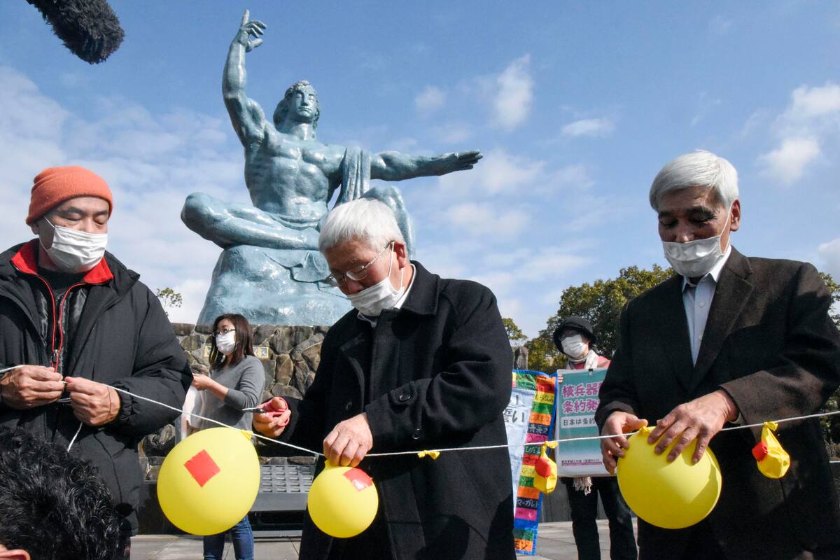 Asistentes desinflan globos simbolizando la esperanza de neutralizar y destruir la ojivas nucleares, durante un acto en el Parque de la Paz de Nagasaki, en el sur de Japón, el 22 de enero de 2021. (Kyodo News via AP)