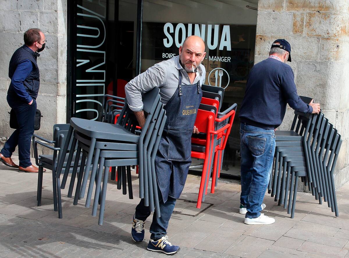 Un empleado de un restaurante carga con sillas mientras prepara la terraza de un restaurante, en Bayona, en el suroeste de Francia, el 18 de mayor de 2021. (AP Foto/Bob Edme)