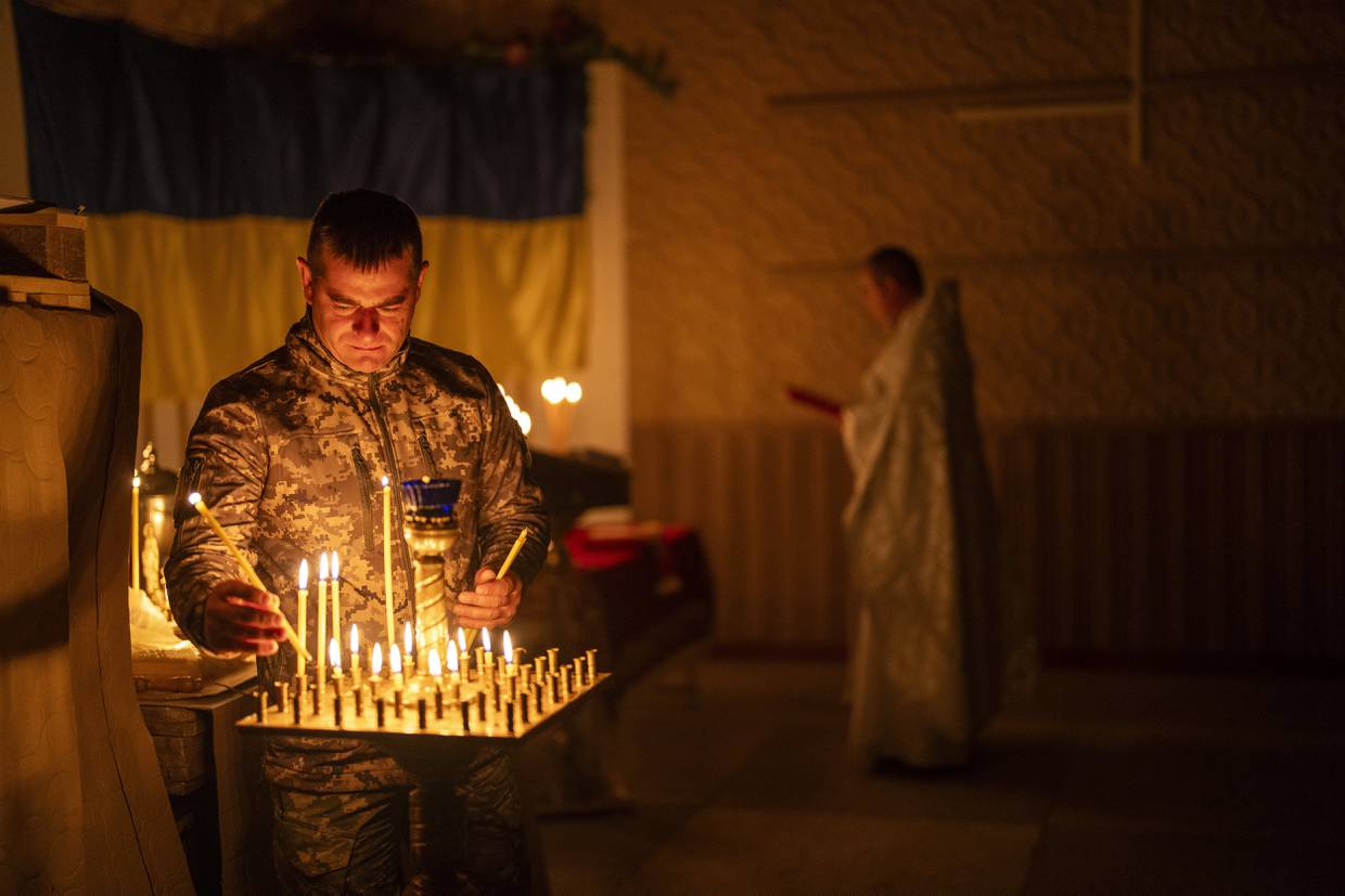Un militar ucraniano de la 72da Brigada Mecanizada Separada enciende velas durante una ceremonia de la Pascua ortodoxa cristiana, en la región de Donetsk, Ucrania, el sábado 4 de mayo de 2024. (AP Foto/Francisco Seco)
