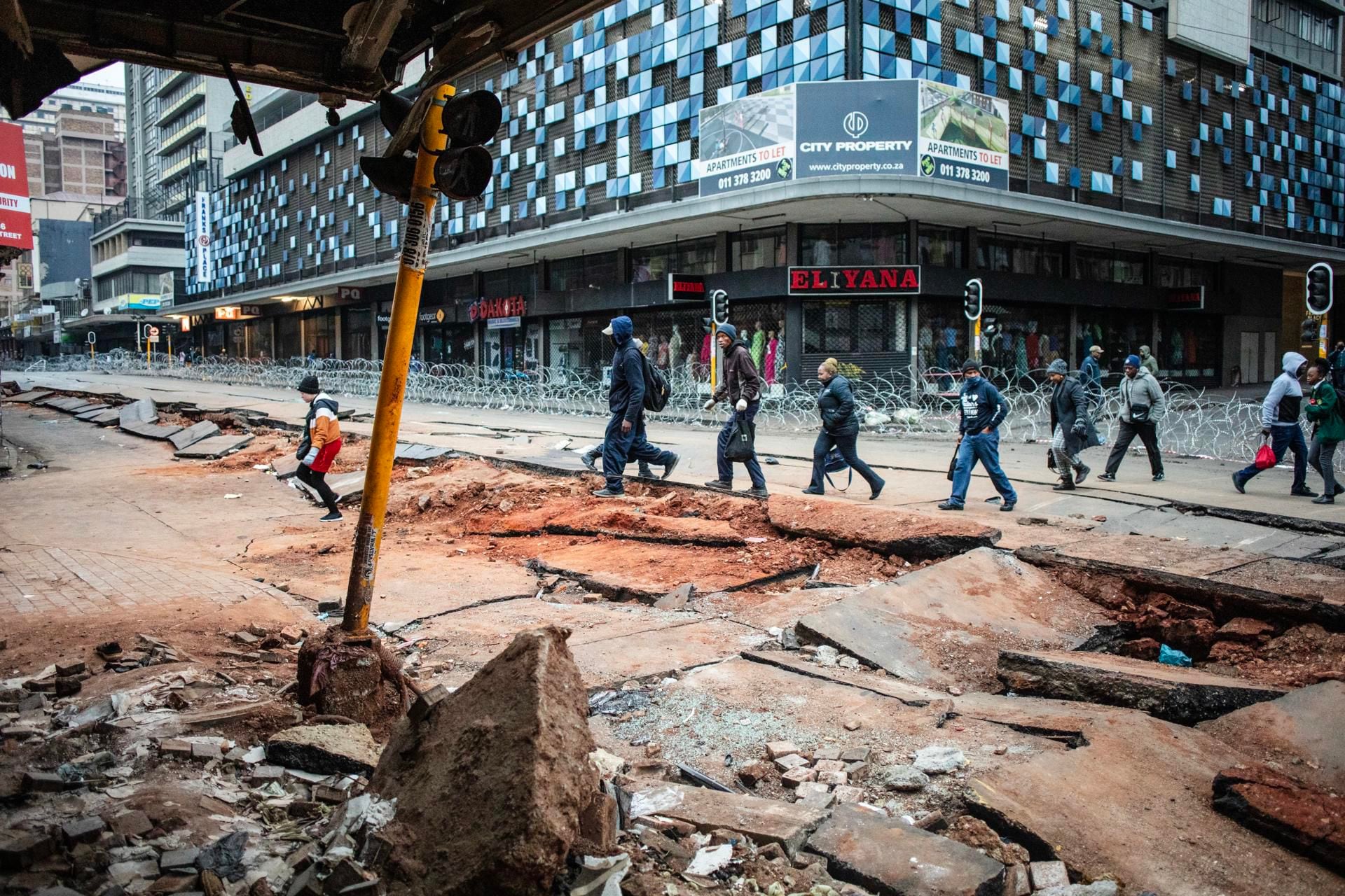 Johannesburg (South Africa), 21/07/2023.- People walk along a damaged street following an underground gas explosion, in Bree Street, downtown Johannesburg, South Africa, 21 July 2023. An underground gas explosion on 19 July killed 1 person and injured at least 48 people. Latest reports indicate that local authorities believe the cause of the Johannesburg CBD explosion was igniting a mixture of gas from methane, natural gas, and a commercial gas line within the storm water system. (tormenta, Sudáfrica, Johannesburgo) EFE/EPA/KIM LUDBROOK
